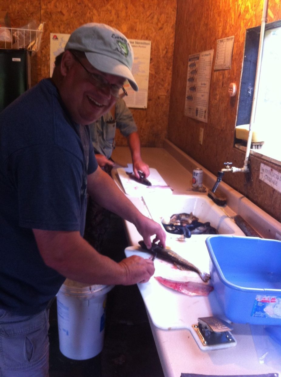 man helping Cliff Wagenbach clean fish