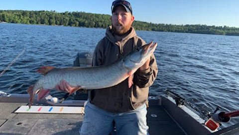 Man holding musky in boat