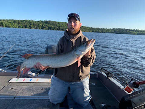 Man holding musky in boat